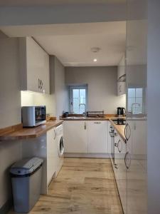a kitchen with white cabinets and a counter top at Amazing coastal & sunset views in Eryri (Snowdonia) in Llanllyfni