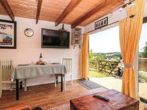 a dining room with a table and a tv on the wall at Dart View Hideout in Totnes