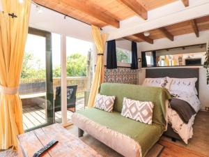 a bedroom with a green couch and a balcony at Dart View Hideout in Totnes