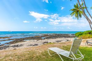a white chair sitting on the grass near the beach at Kona Bali Kai #418 in Kailua-Kona