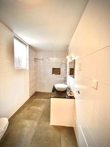 a white bathroom with a sink and a toilet at Quinta das Carpas in Tavira