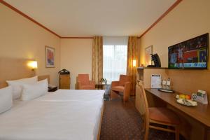 Habitación de hotel con cama blanca grande y escritorio. en Sure Hotel by Best Western Hilden-Düsseldorf, en Hilden