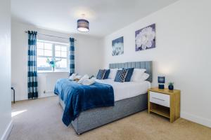 een slaapkamer met een groot bed en een blauwe deken bij Spacious 4-Bed Townhouse in Crewe by 53 Degrees Property, Ideal for Contractors & Business, FREE Parking - Sleeps 8 in Crewe