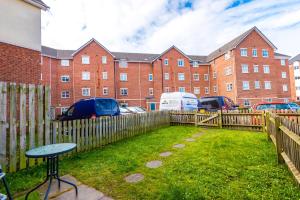 a fence and a table in a yard with a building at Spacious 4-Bed Townhouse in Crewe by 53 Degrees Property, Ideal for Contractors & Business, FREE Parking - Sleeps 8 in Crewe