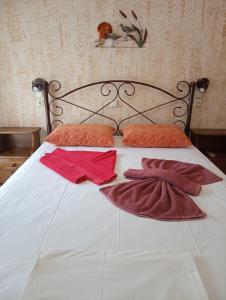 a white bed with red pillows and towels on it at Nektaria on the Beach in Fournoi