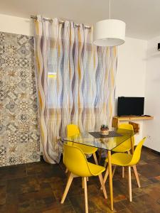 a dining room with a glass table and yellow chairs at Giramondo in Senigallia