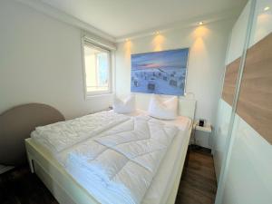 a bedroom with a white bed with a painting on the wall at Panoramic App B10-7 in Sierksdorf +13 photos
