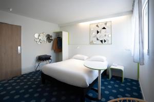 een slaapkamer met een wit bed en een tafel bij ibis Styles Fougeres in Beaucé