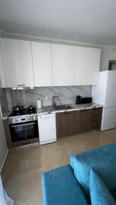 a kitchen with white cabinets and a blue couch at Beach House Holiday in Neoi Epivates