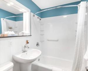 a white bathroom with a sink and a shower at Top Notch Inn in Gorham