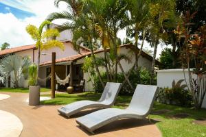 2 sillas sentadas en un patio frente a una casa en Pousada Villa Palmeira Azul, en Arraial d'Ajuda