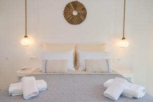 una camera da letto con un letto con cuscini bianchi e un orologio di Orion Milos a Pollonia