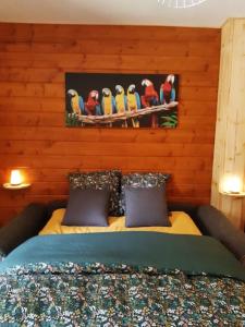a bedroom with a bed with birds on a wooden wall at Gîte du Chalet - Le studio en pleine nature 