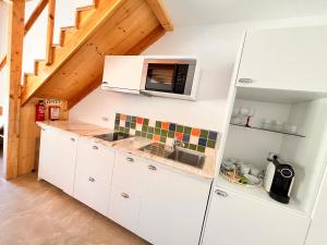 a kitchen with white cabinets and a microwave at Quinta das Carpas in Tavira