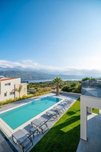 a swimming pool with lounge chairs next to a house at Jarko Luxury Houses in Argoulidhés