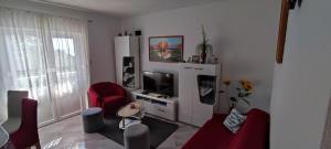 a living room with red chairs and a television at Apartment Biondic in Senj