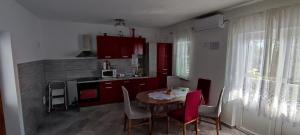 a kitchen with a table and chairs and a kitchen with red cabinets at Apartment Biondic in Senj