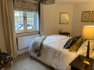 a bedroom with a bed and a window at Cosy luxury 3 bed cottage in The Surrey Hills in Ockley