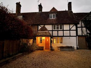 a black and white house with a red door at Cosy luxury 3 bed cottage in The Surrey Hills in Ockley