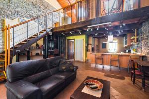 a living room with a leather couch and a kitchen at Ardenga Guest House in Montechiarugolo