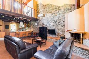 sala de estar con muebles de cuero y pared de piedra. en Ardenga Guest House, en Montechiarugolo