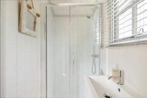 baño blanco con ducha y lavamanos en Apple Blossom, Devon Hideaways, en Kenton