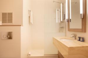 La salle de bains blanche est pourvue d'un lavabo et d'un miroir. dans l'établissement Kyriad Paris Est - Bois de Vincennes, à Saint-Maurice