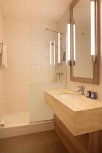 a bathroom with a sink and a tub and a mirror at Kyriad Paris Est - Bois de Vincennes in Saint-Maurice