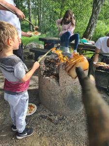 um rapaz a tirar uma fotografia a uma mulher a cozinhar comida sobre uma fogueira. em Strandängen rustisk stuga em Osby