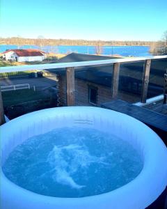 una vasca idromassaggio su una terrazza con vista sull'acqua di Strandängen rustisk stuga a Osby