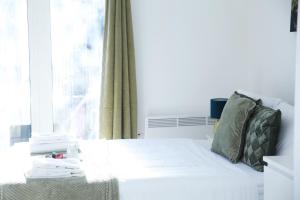 - un lit blanc dans une chambre avec fenêtre dans l'établissement Central Harrow Cozy Apartment with free parking, à Harrow on the Hill
