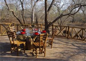 a wooden table and chairs with red cups on it at Les 3 Marulas in Marloth Park