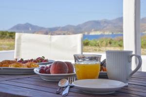 a table with a plate of fruit and a glass of orange juice at Orion Milos in Pollonia