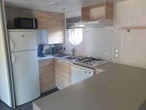 a kitchen with white appliances and a white refrigerator at Camping Pré Vologne in Granges-sur-Vologne
