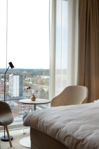 a bedroom with a bed and chairs and a large window at The Wood Hotel by Elite, Spa & Resort in Skellefteå