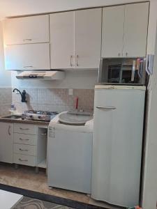 a kitchen with white cabinets and a white refrigerator at Grand Ville Asa sul in Brasilia