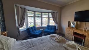 a bedroom with two blue chairs and a bed and a television at The Kimberley B&B in Blackpool