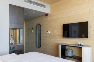 um quarto com uma televisão de ecrã plano numa parede de madeira em The Wood Hotel by Elite, Spa & Resort em Skellefteå