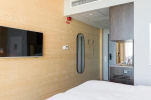 Cet appartement comprend une chambre dotée d'un mur en bois, d'un lit et d'une cuisine. dans l'établissement The Wood Hotel by Elite, Spa & Resort, à Skellefteå