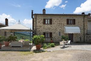 a stone house with a table and chairs and an umbrella at Villa Olivi - Subbiano, Toscana, Pool And Nature in Subbiano