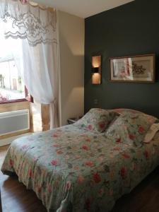 1 dormitorio con 1 cama con colcha de flores y ventana en Maison Lambert, en Domme