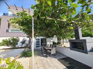 a tree in front of a house with a table and a fireplace at Villa Ska in Pula