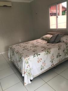 1 dormitorio con 1 cama con colcha de flores y ventana en Casa em tibau RN, en Tibau do Sul