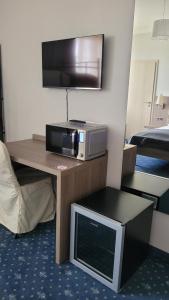 Zimmer mit einer Mikrowelle und einem TV auf dem Tisch in der Unterkunft Drei Bären Inn in Aichach
