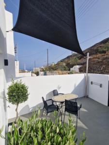 un patio con mesa y sillas en una pared blanca en Luxury Canava en Emporio Santorini