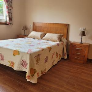 a bedroom with a bed with a floral bedspread and two night stands at Casa Maside Orense in Maside