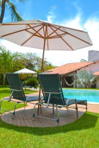 dos sillas y una sombrilla junto a una piscina en Pousada Villa Palmeira Azul, en Arraial d'Ajuda
