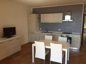 cocina con mesa de comedor y sillas blancas en Residence Lentischi, en Castelsardo