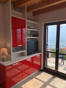 ein Wohnzimmer mit roten Schränken und einem TV in der Unterkunft La Quiete 56 Lake view Apartment by Gardadomusmea in Tremosine sul Garda