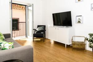a living room with a television on a white cabinet at Sunscape Nature Apt de 1 quarto Ponta do Sol in Ponta do Sol